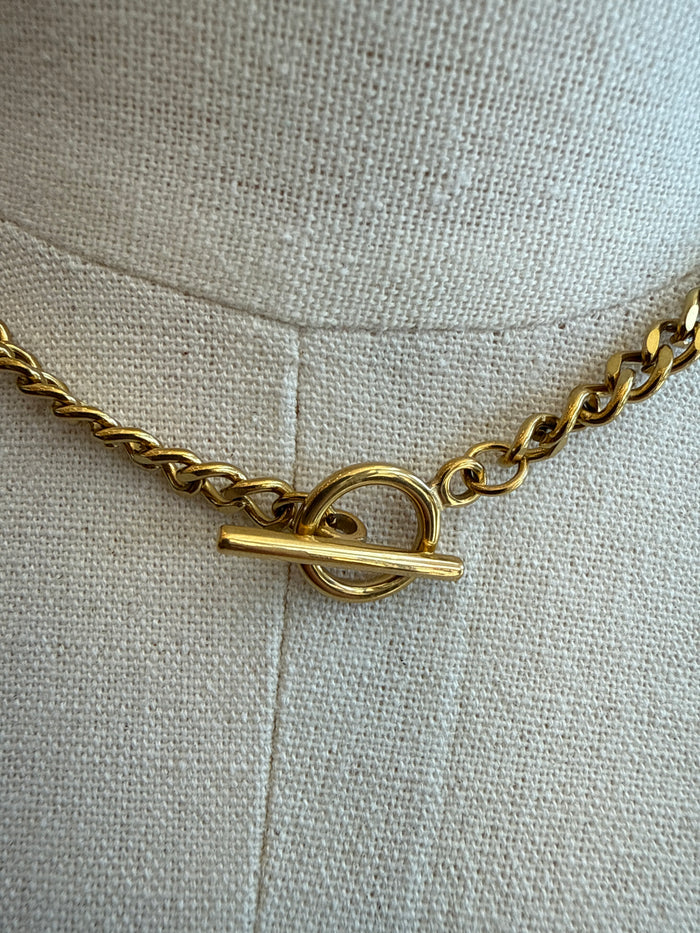 Gold-tone chain necklace with toggle clasp and interlocked ring hardware close-up