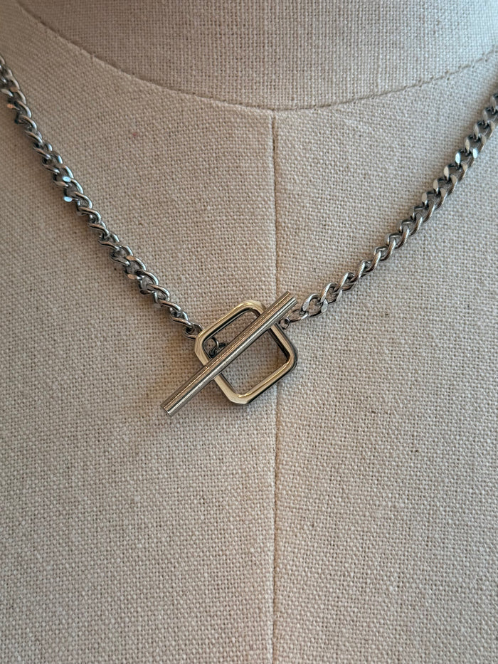 Square toggle clasp close-up on silver-toned linked chain