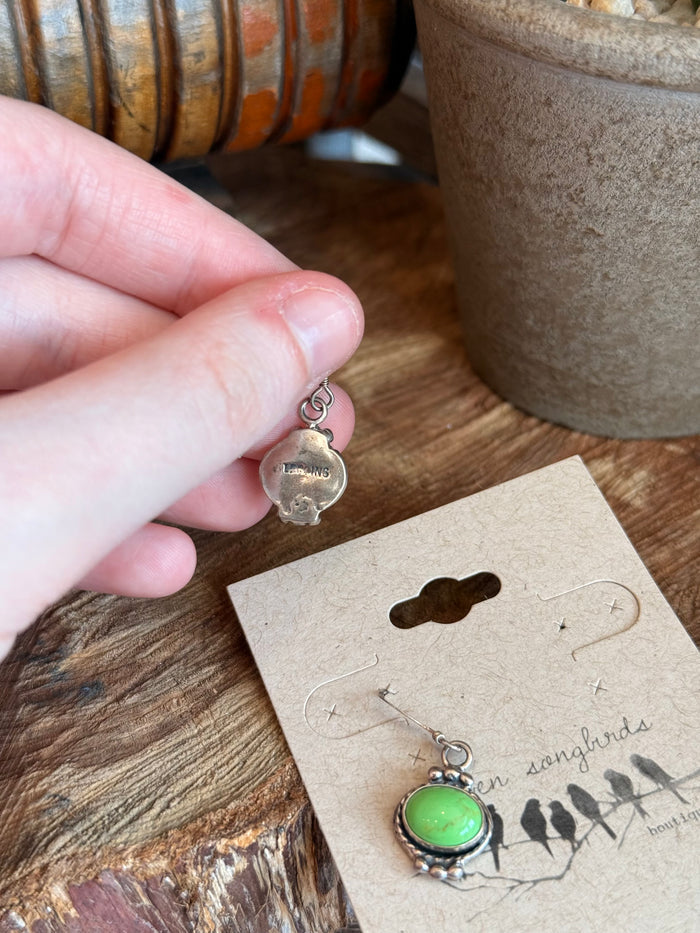 Sterling silver fishhook earring with green oval gemstone bezel, close-up