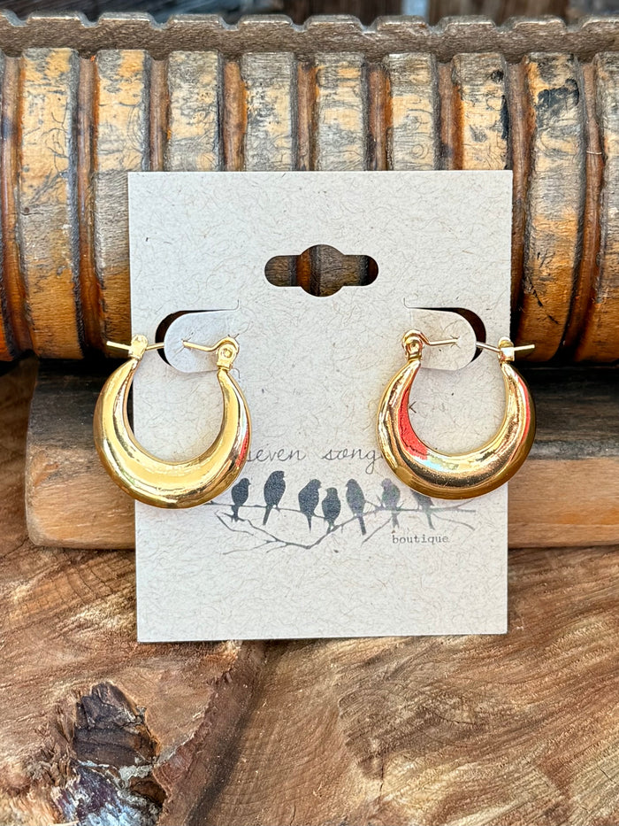 Gold-tone crescent hoop stud earrings with visible backs and loop details on card