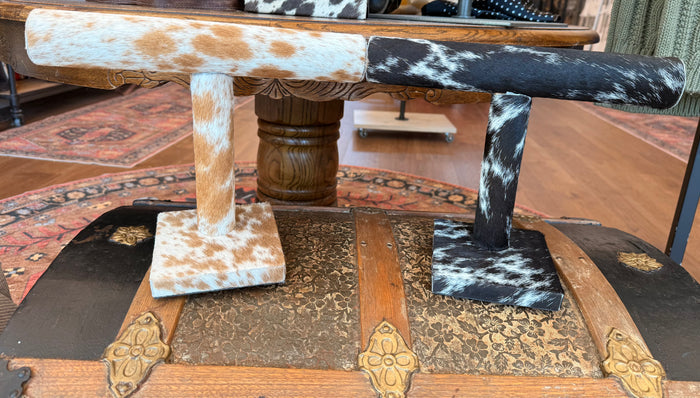 Cowhide bracelet display stand with black-and-white hide top bar and square bases