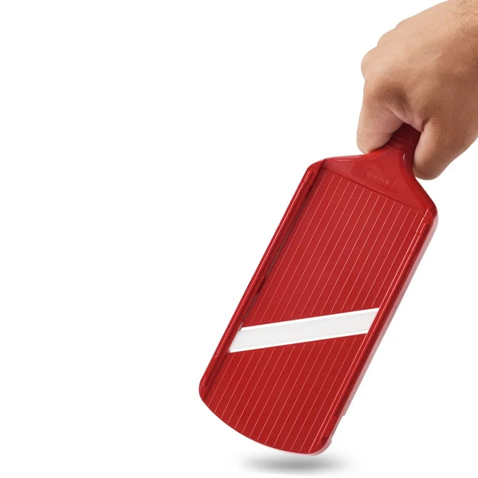 Red kitchen slicer held by a hand on a white background