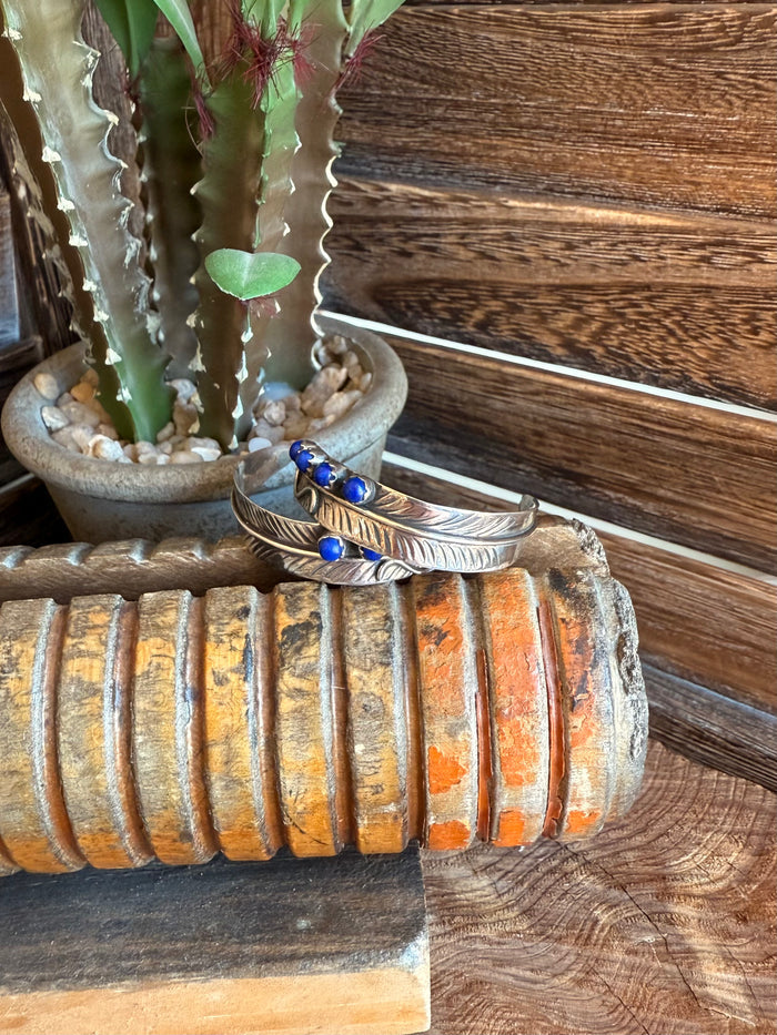 Feather stud earrings with gold-tone leaves and blue lapis-style cabochon stones
