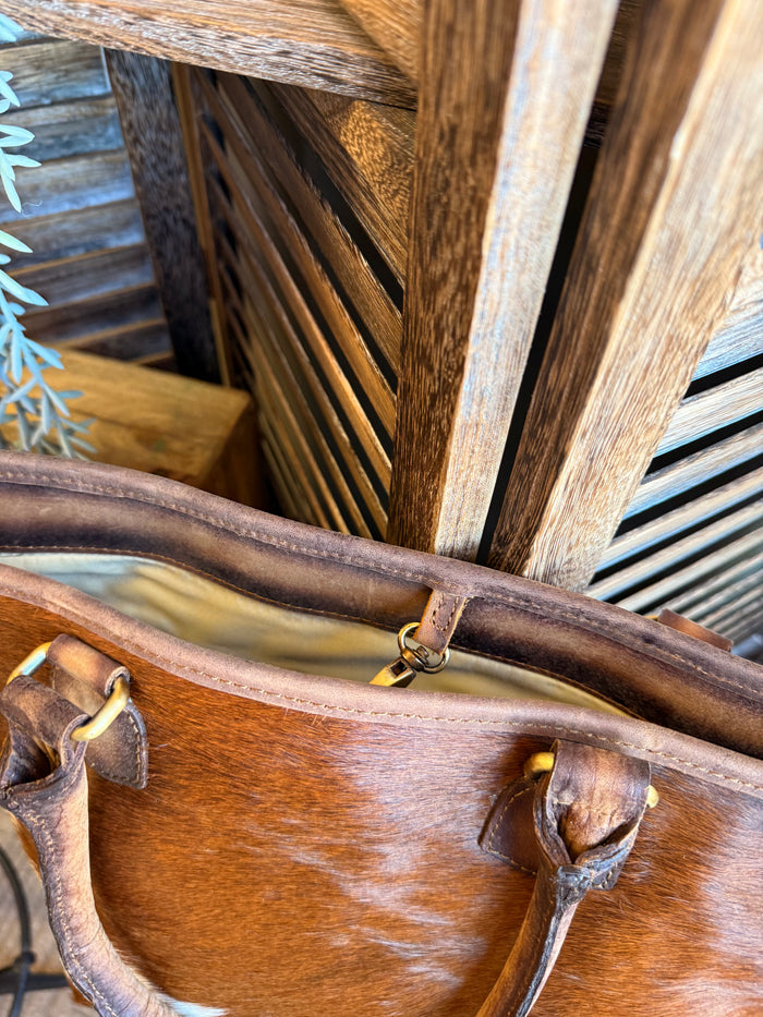 Brown leather top handle with stitching, showing cowhide edge trim