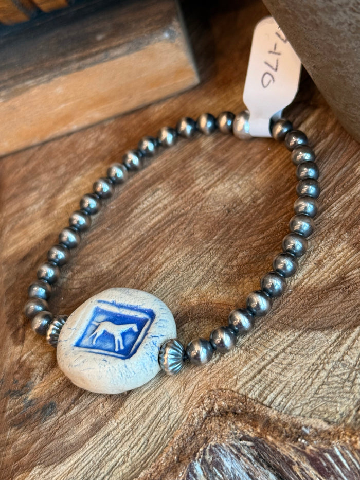 Stretchy beaded bracelet close-up of blue horse ceramic disc centerpiece and metal beads
