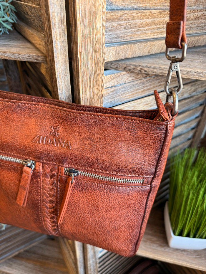 Rusty brown leather crossbody bag showing double zip pockets and stitched vertical divider