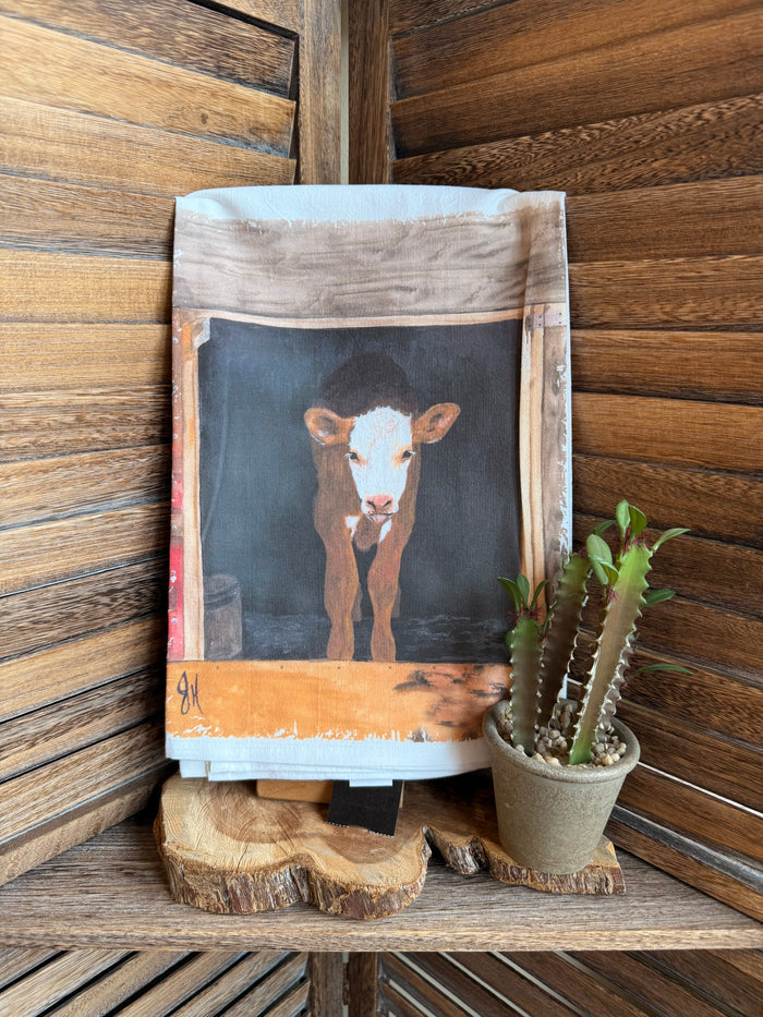 Small watercolor calf tea towel with blue-gray cow illustration and orange ground stripe