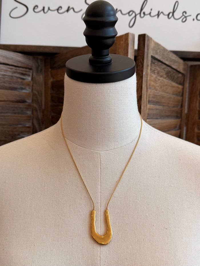 Gold wavy U necklace on mannequin, thin chain and curved U pendant