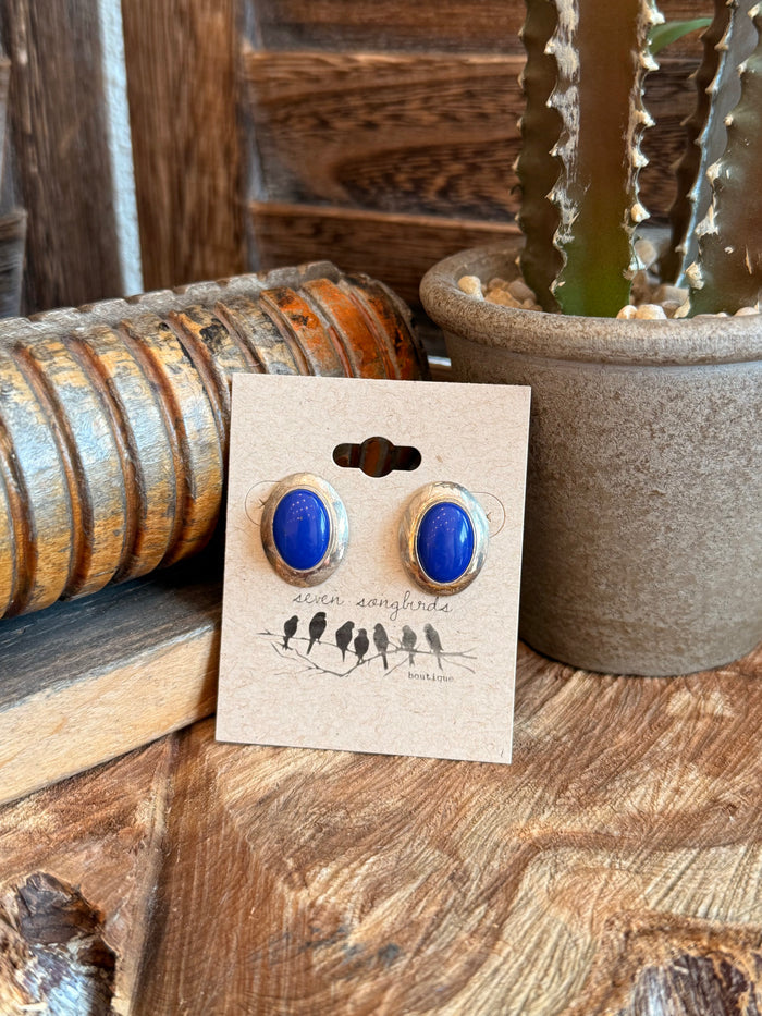 Blue oval lapis stud earrings in gold-tone settings, shown on display card