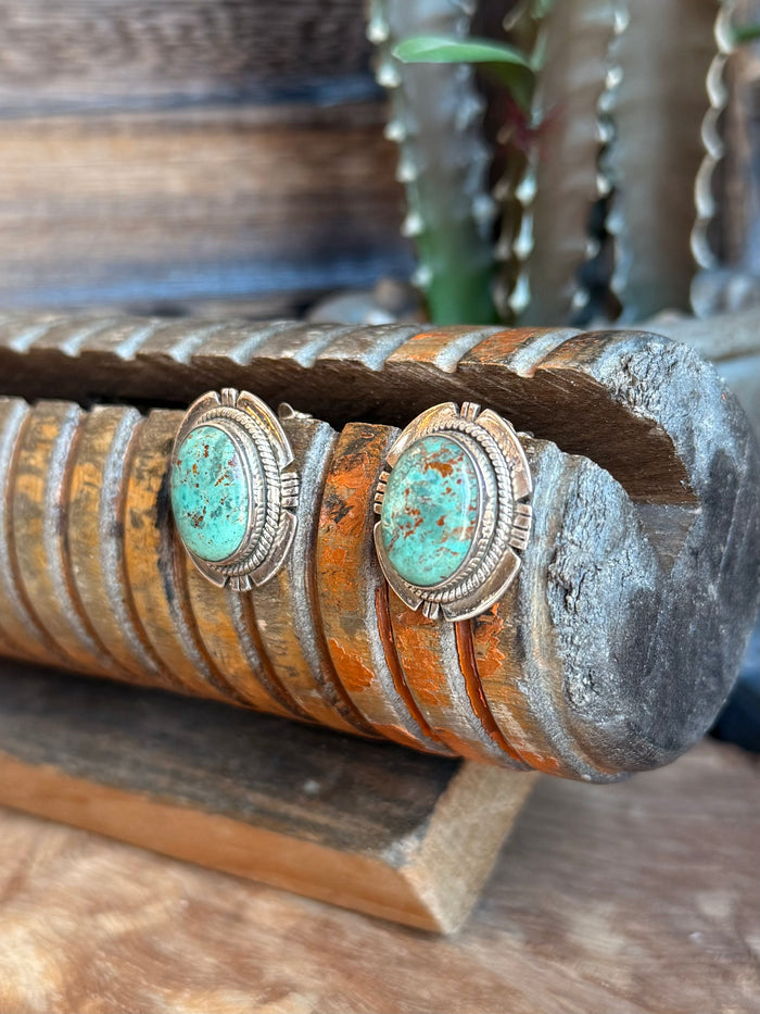 Side view of turquoise cabochon stud earrings with textured silver frame, pair