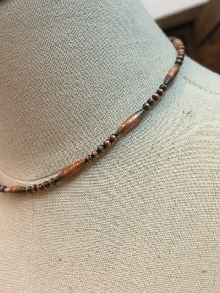 Close-up of copper torpedo bead necklace with black bead row and copper centerpiece