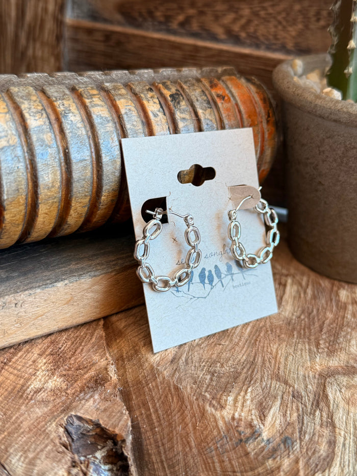 Silver-tone round stud chain earrings with dangling links, shown on card
