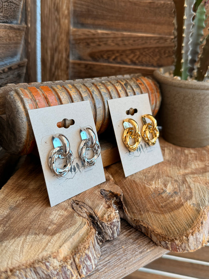 Twisted round stud earrings in gold and silver, shown on two display cards