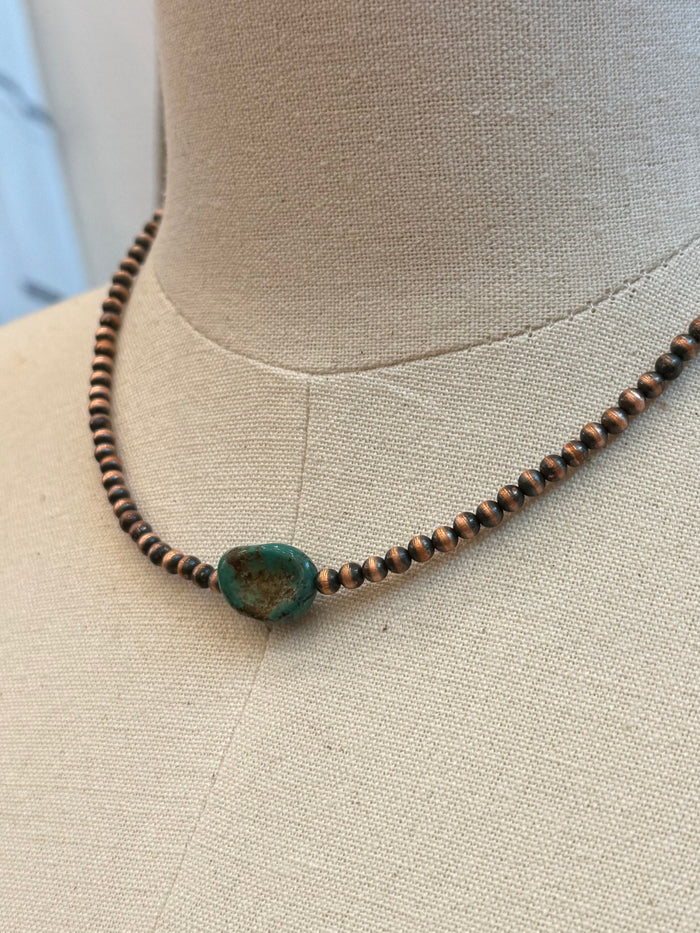 Close-up of turquoise copper bead necklace with central turquoise stone bead