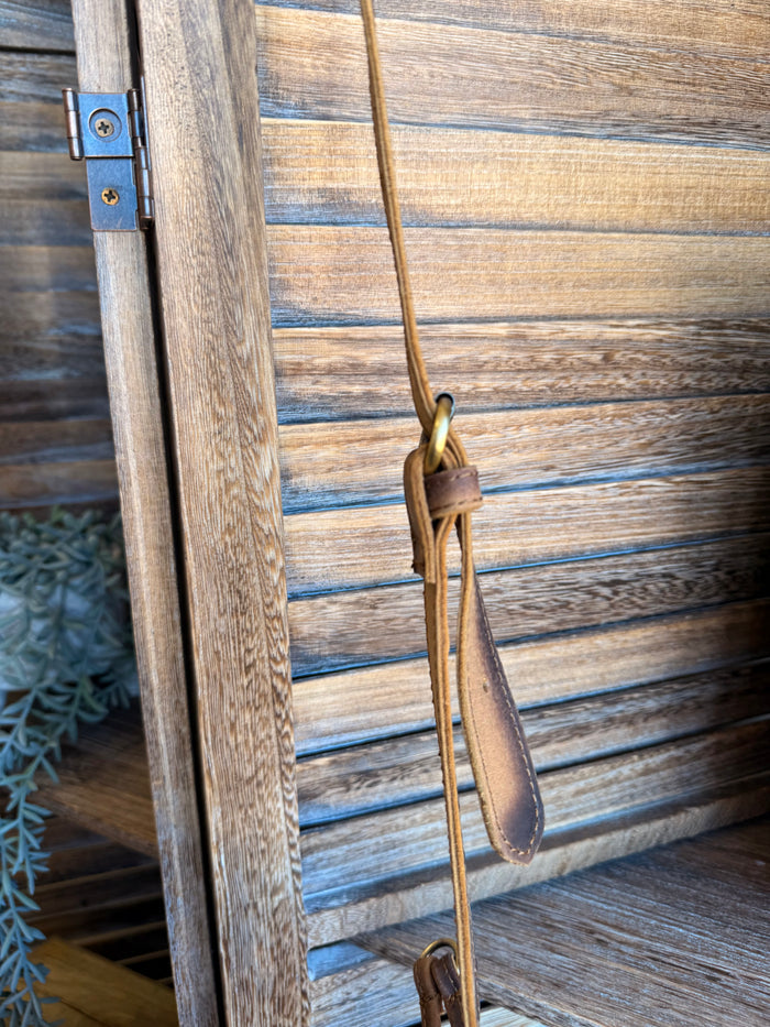Cowhide purse crossbody strap detail with brass-tone hardware and hanging loop