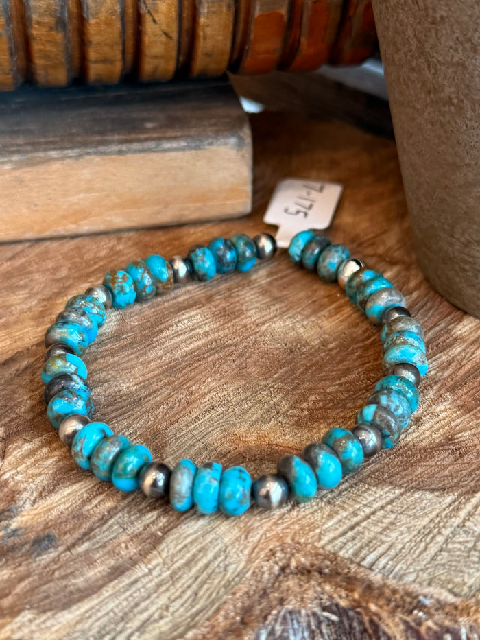 Turquoise and silver bead stretch bracelet on wooden background