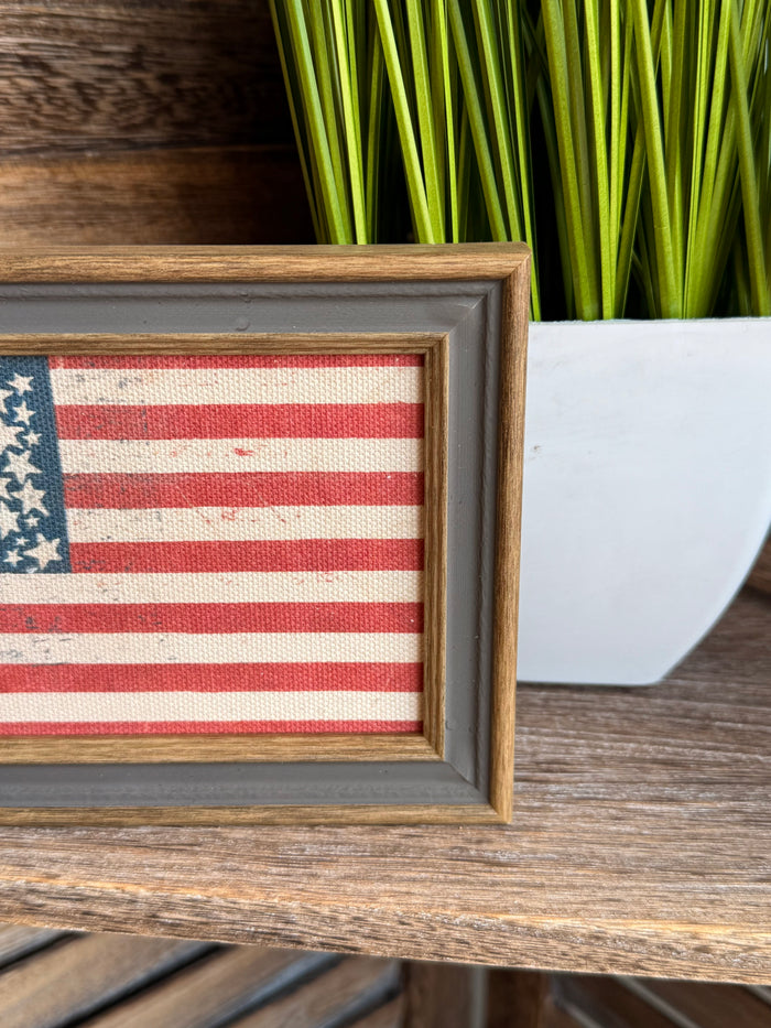 Close-up of framed American flag artwork showing blue canton and red stripes
