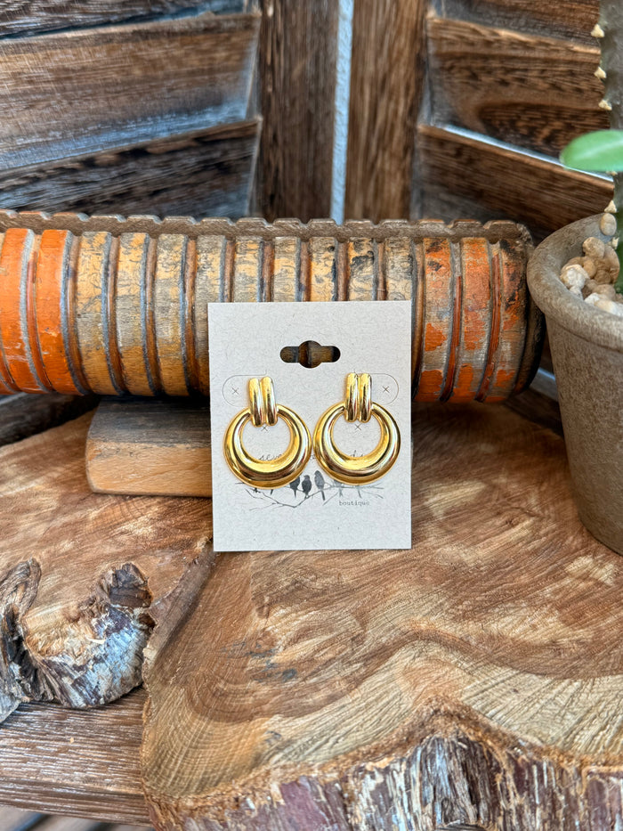 Gold-tone hoop stud earrings with circular loops, shown on display card