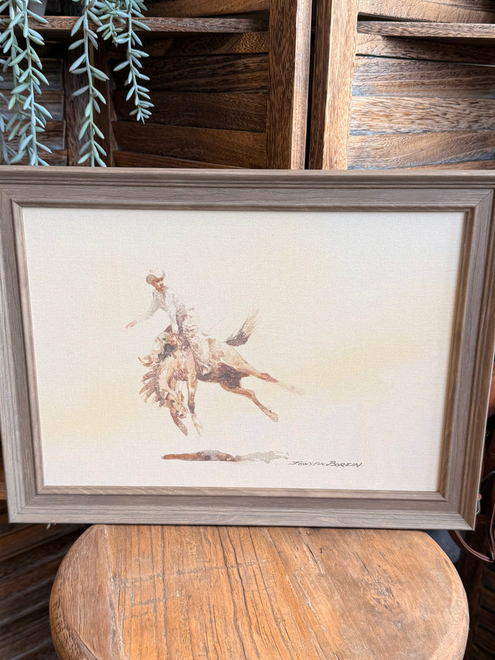 Framed cowboy and bucking horse artwork with beige mat and gray wood frame, landscape view