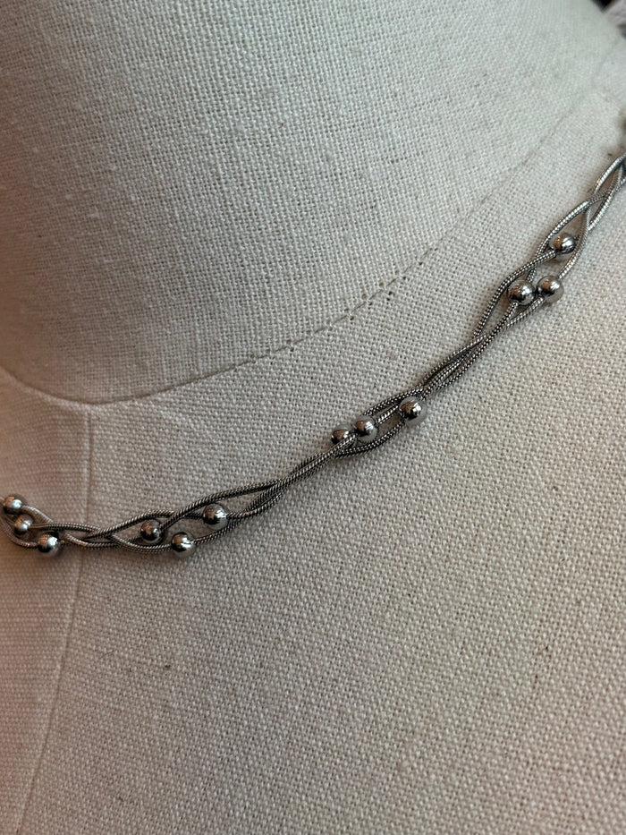 Stainless steel chain necklace with small bead accents and rounded links, close-up