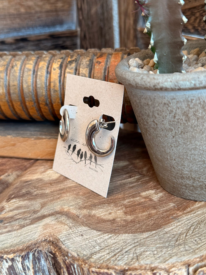 Silver half-curved hoop stud earrings, side view of one hoop on backing card
