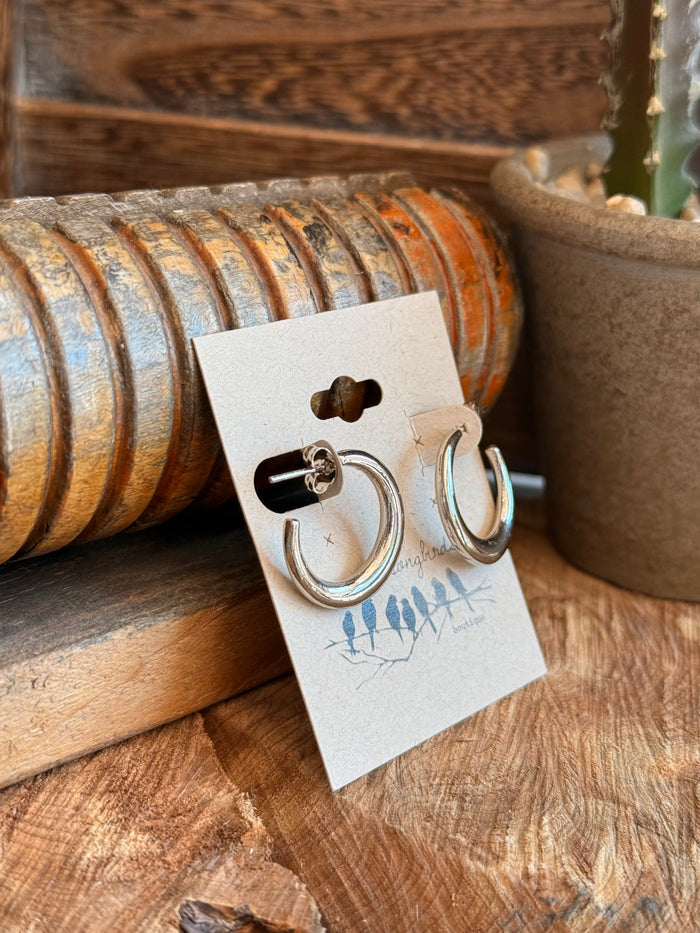 Silver stainless steel round hoop stud earrings with small clasp, angled view.