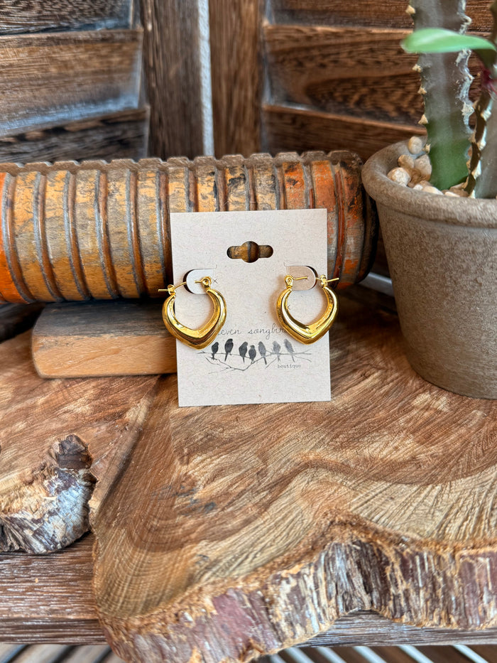 Gold-tone smooth half-hoop earrings with hinged clasp, shown on a display card