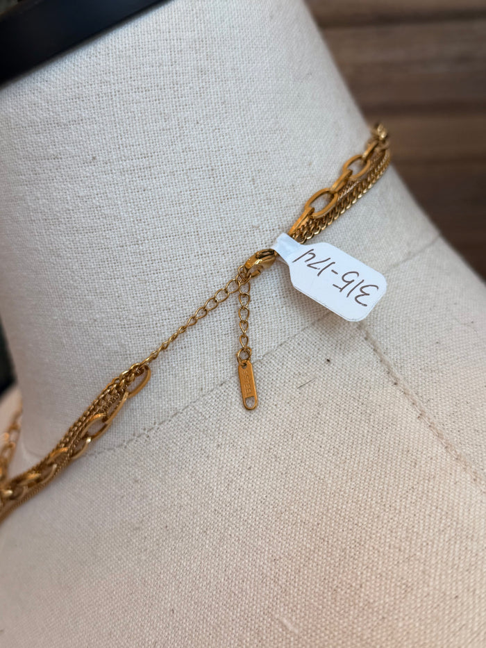 Gold-plated chain necklace detail with small coin charm and clasp