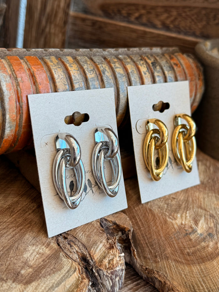 Double round stud earrings in gold: oval double-hoop studs on white display card