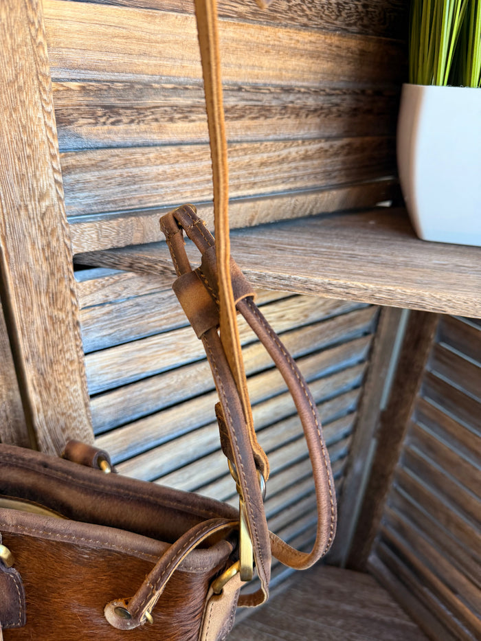 Brown leather crossbody strap with metal clips attached to cowhide purse