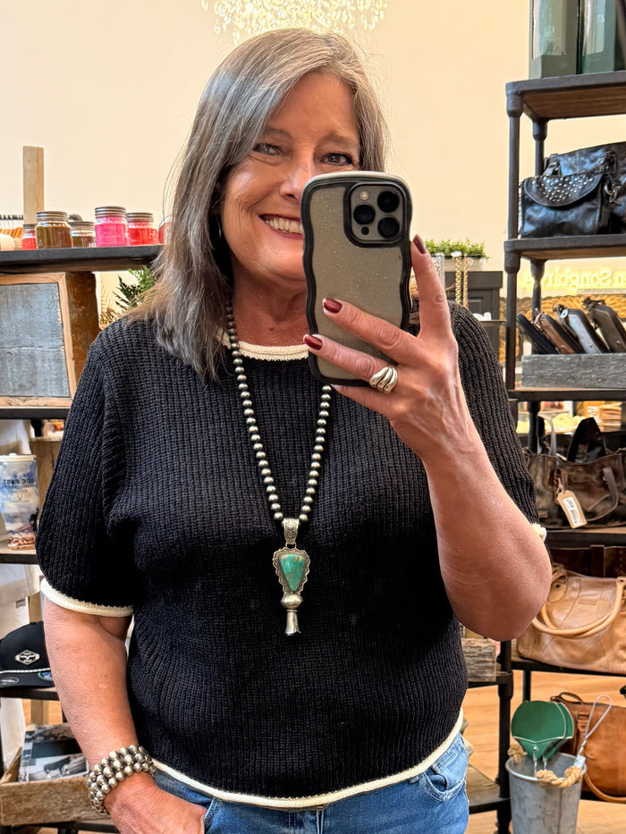 Black short-sleeve knit sweater with white ribbed trim at hem and cuffs