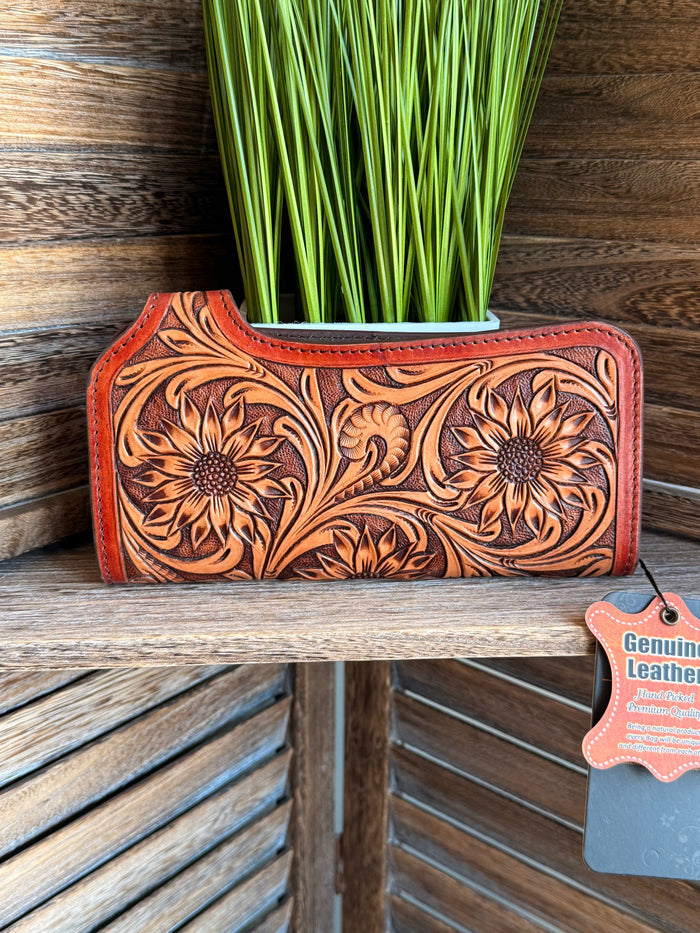 Tooled leather clutch wallet on display, floral embossing, snap strap, orange-brown.