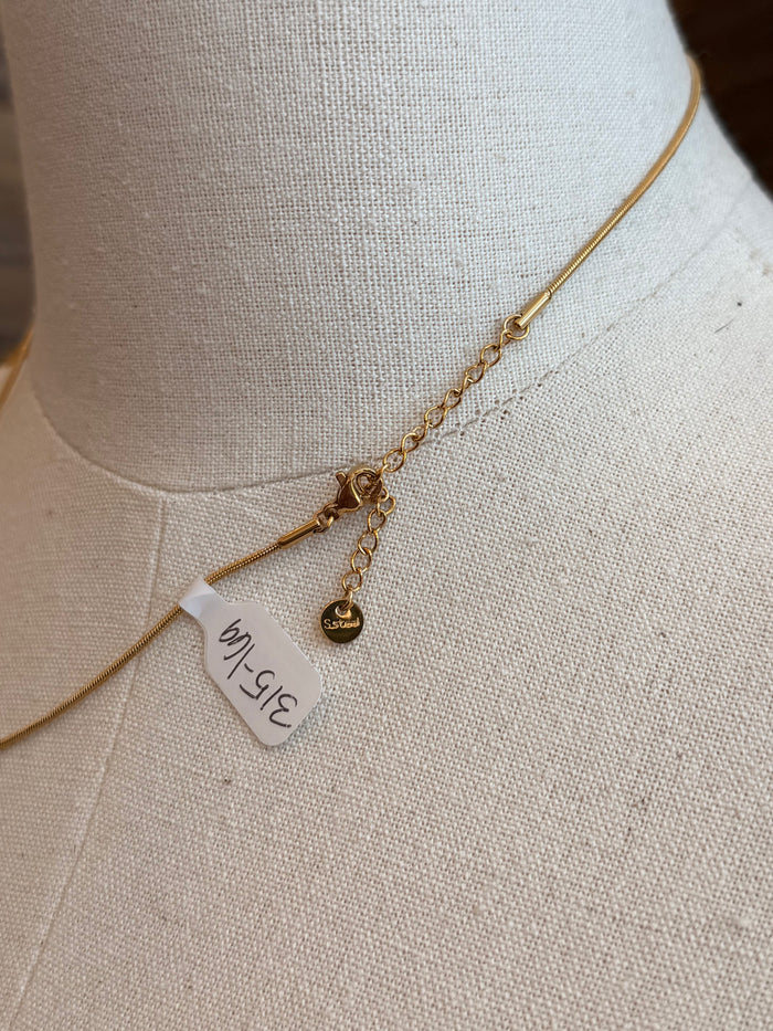 Gold wavy U necklace close-up showing chain links and small charm tag