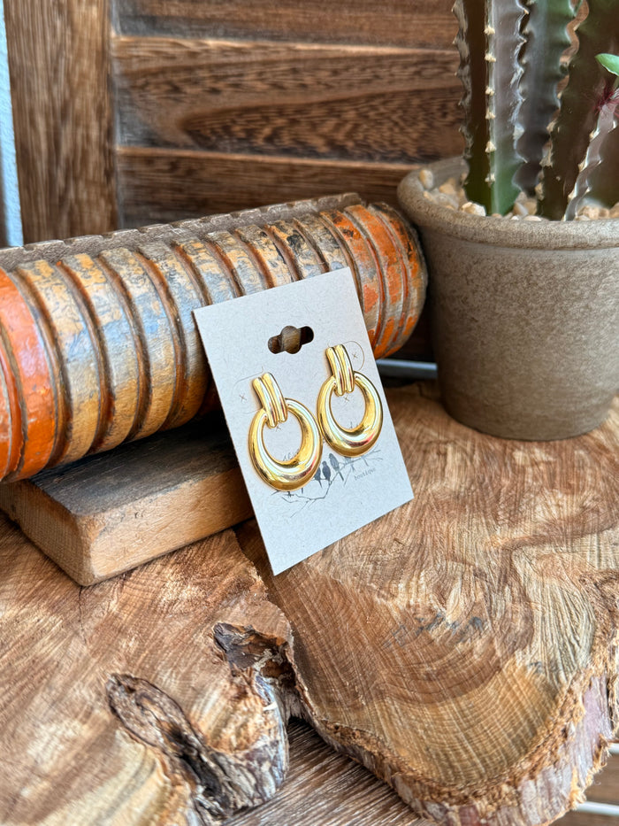 Gold-tone hoop stud earrings with circular loops, angled view on display card