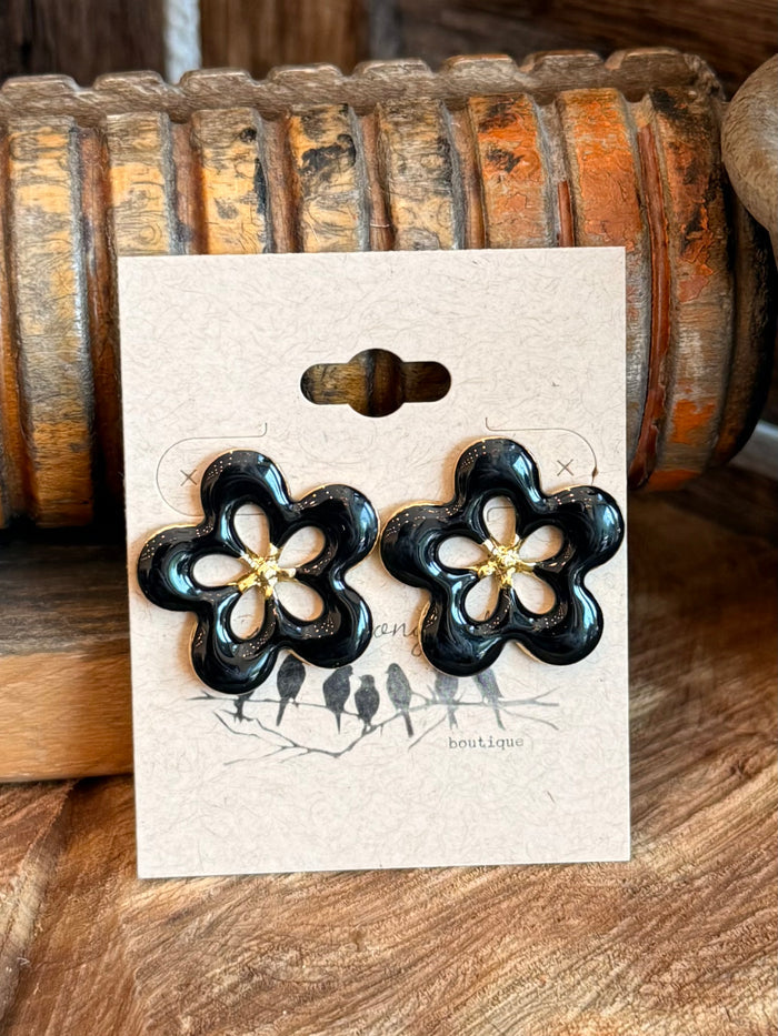 Black flower stud earrings with gold center, stainless steel, front view on card