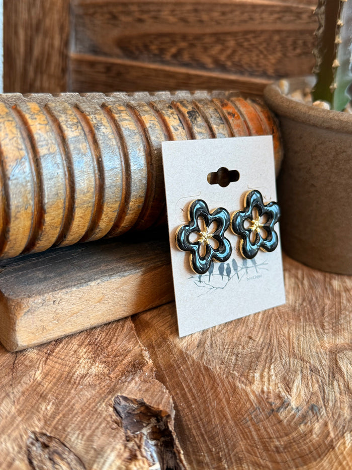 Black and gold flower stud earrings, stainless steel, angled side view on card