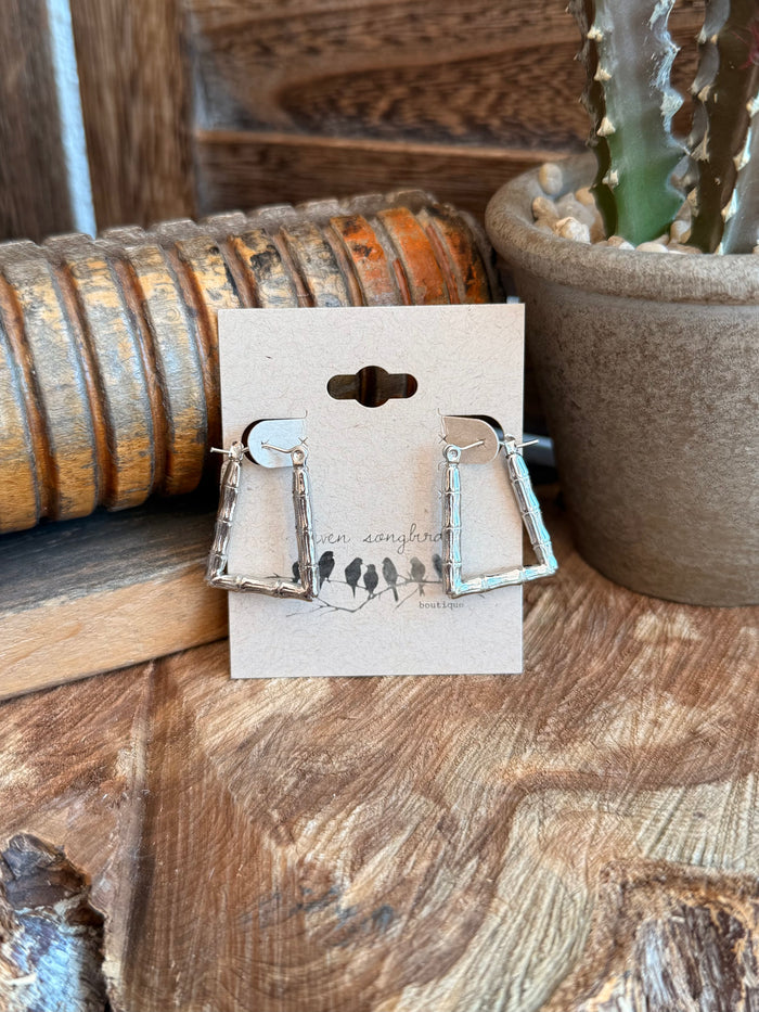 Silver-tone textured trapezoid drop earrings on display card, hanging frames and hooks