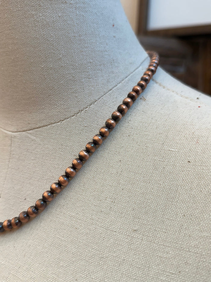 Copper bead necklace close-up with round beads along the chain