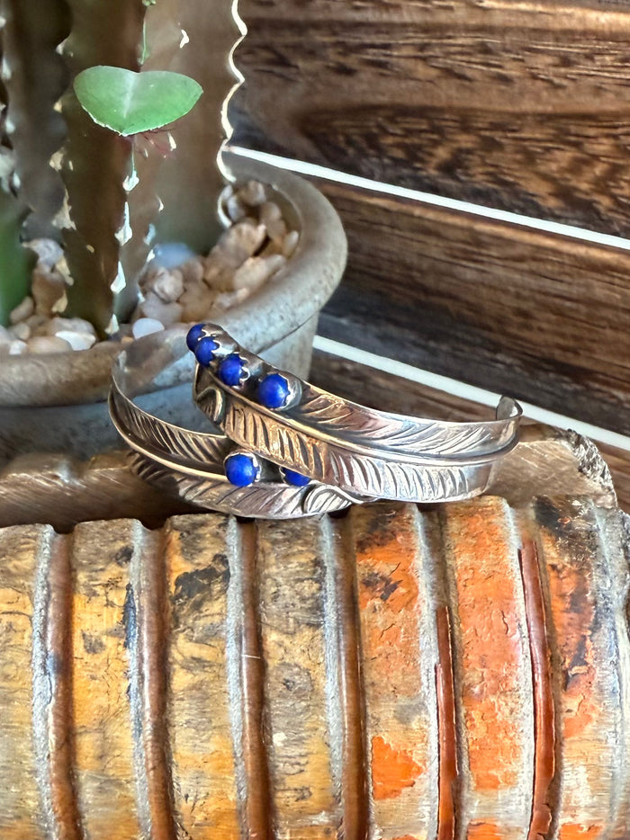 Gold-tone feather earrings with three blue lapis-style stud stones