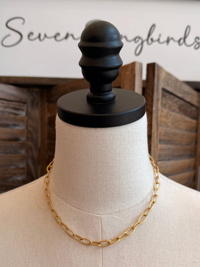 Gold-plated chain necklace with oval link design on a mannequin bust