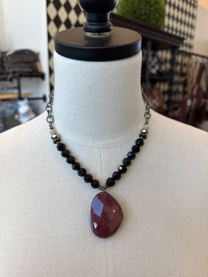 Black beaded pendant necklace with red oval crystal stone centerpiece on chain
