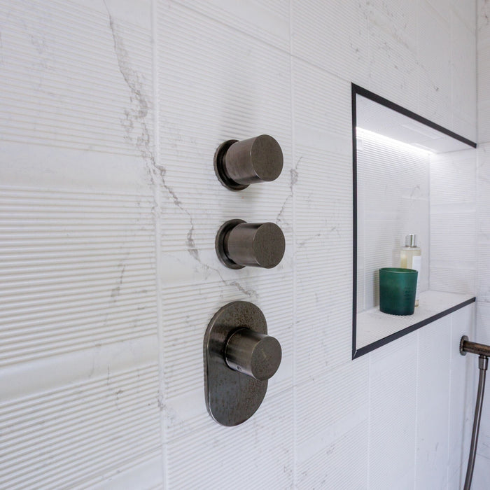 Textured white marble effect wall tiles and a shower valve
