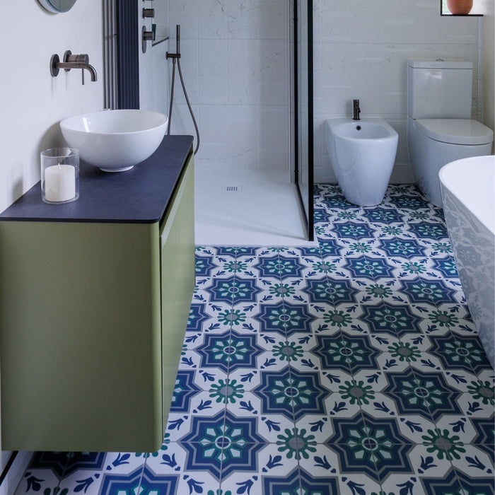 Bathroom with blue and white patterned tiles on the floor, green vanity, and white toilet.