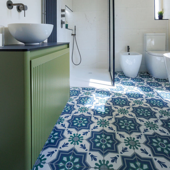 Bathroom with green and blue patterned tiles on the floor, white sink, and toilet.
