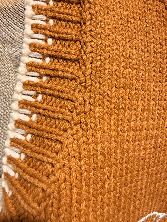 Rust knit sweater vest detail with striped trim and contrast white edging