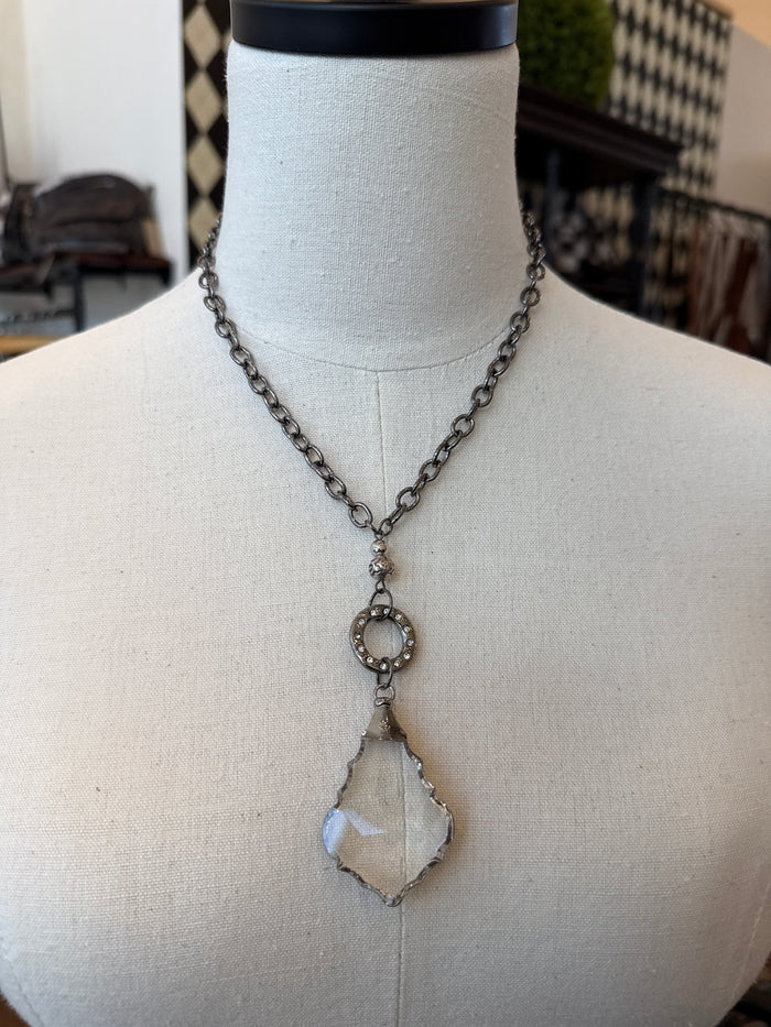 Silver-tone chain necklace with round filigree charm and faceted crystal drop pendant.