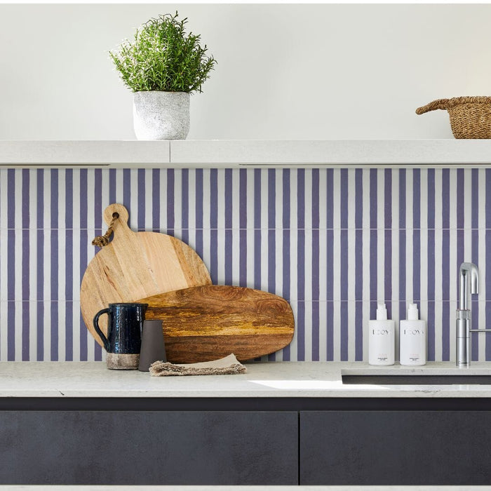 Modern kitchen with striped blue and white tiled backsplash, wooden cutting boards, and kitchen items.