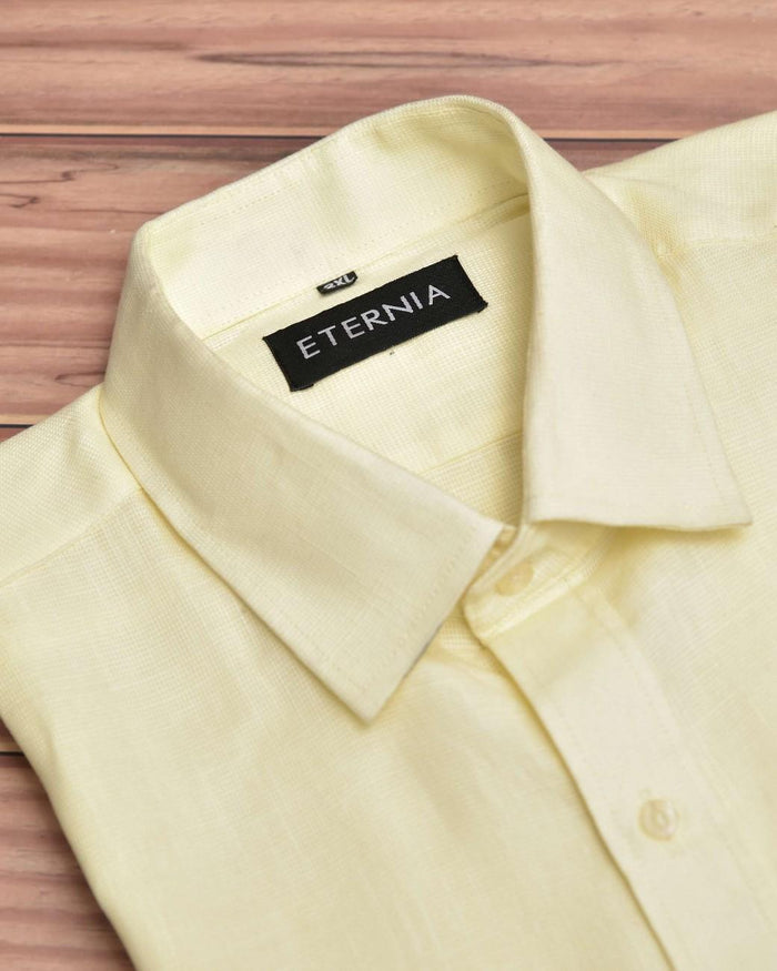 Men's butter yellow linen shirt close-up of ETERNIA neck label and pointed collar.