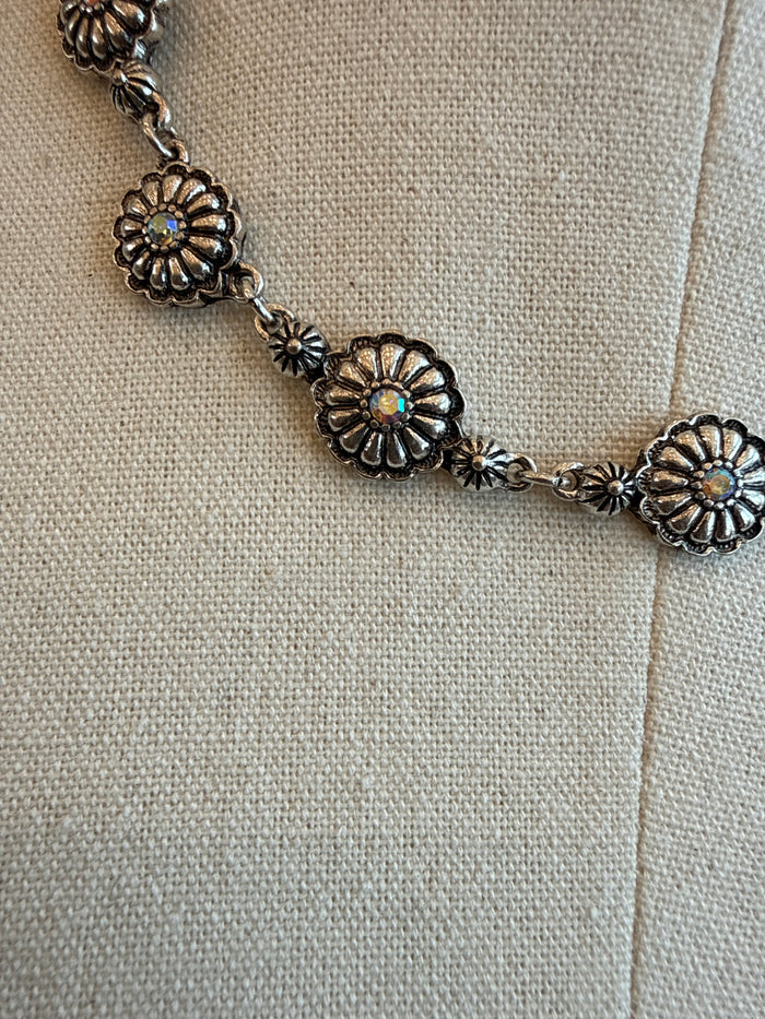Gold-tone floral crystal necklace close-up with five petal medallions and chain