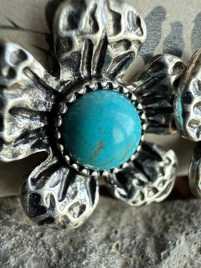 Close-up of turquoise round cabochon flower on silver textured fishhook earring
